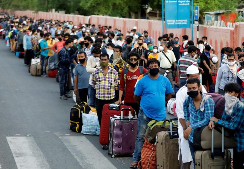 Migrant workers and their families wait in lines outside a railway station to board a train to their home state West Bengal, after authorities eased lockdown restrictions that were imposed to slow the spread of the coronavirus disease (COVID-19), in Ahmedabad, June 18, 2020. REUTERS/Amit Dave  